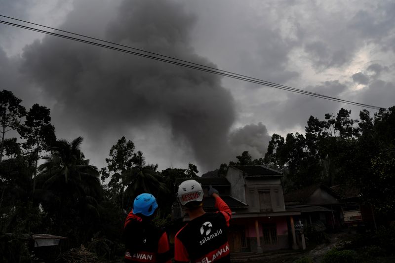 Volunteers look as volcanic ash spews from Mount Semeru volcano in Sumber Wuluh village, Lumajang, East Java province, Indonesia on Sunday. The volcano was active again on Monday.