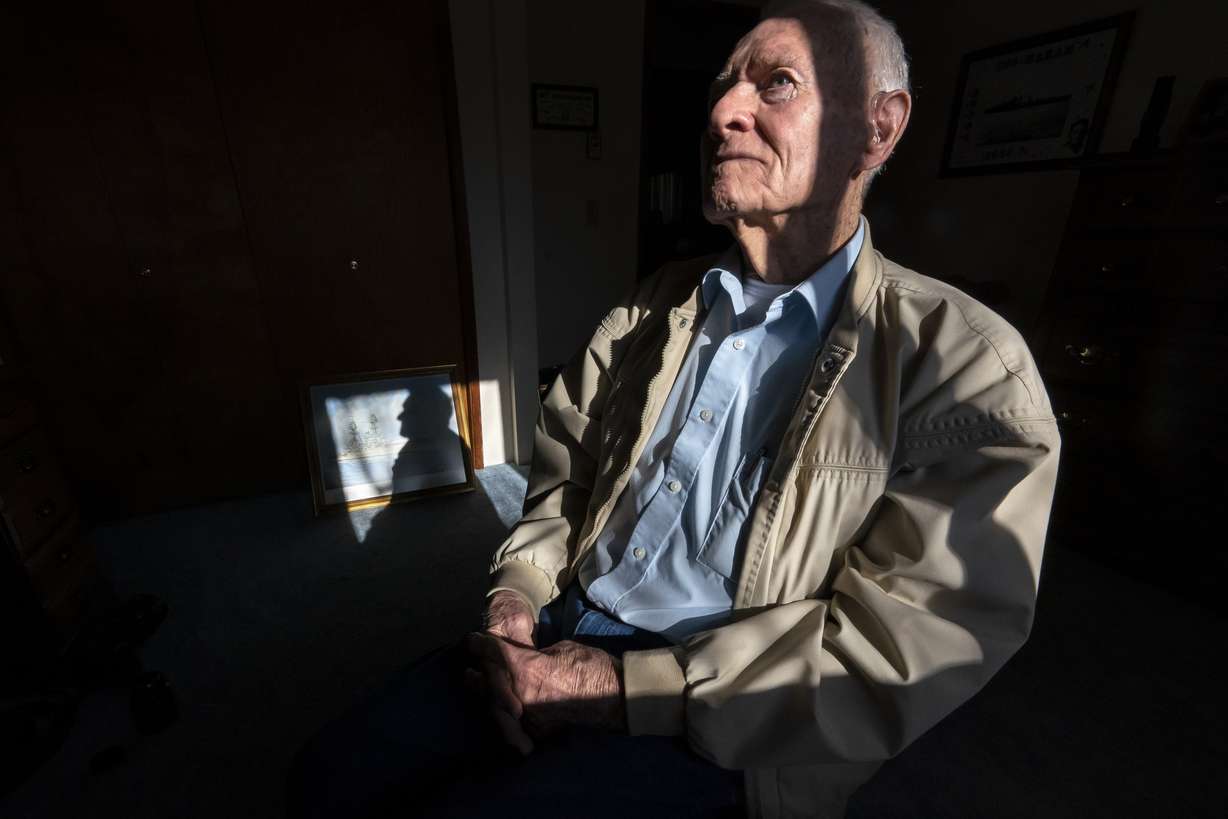 Pearl Harbor survivor and World War II Navy veteran David Russell, 101, poses for a photo along with a painting of the USS Oklahoma at his home on Monday, Nov. 22, 2021, in Albany, Ore.