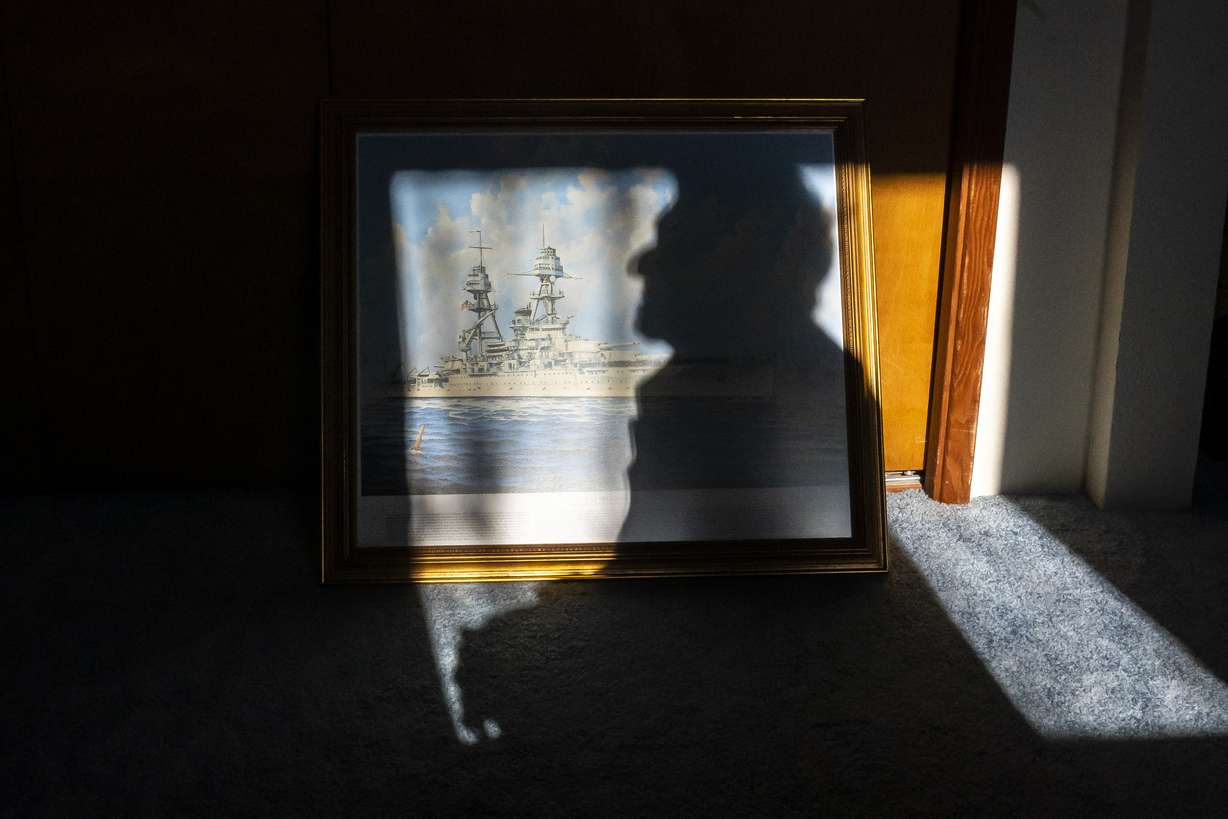 Pearl Harbor survivor and World War II Navy veteran David Russell, 101, poses for a photo along with a painting of the USS Oklahoma at his home on Monday, Nov. 22, 2021, in Albany, Ore.