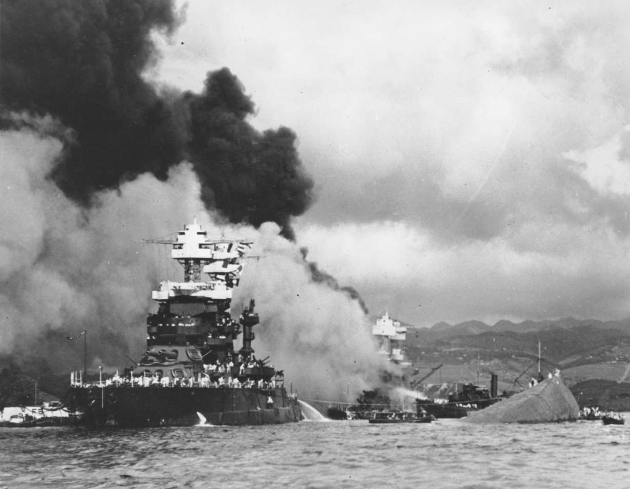 Part of the hull of the capsized USS Oklahoma is seen at right as the battleship USS West Virginia, center, begins to sink after suffering heavy damage on Dec. 7, 1941, while the USS Maryland, left, is still afloat in Pearl Harbor, Oahu, Hawaii.