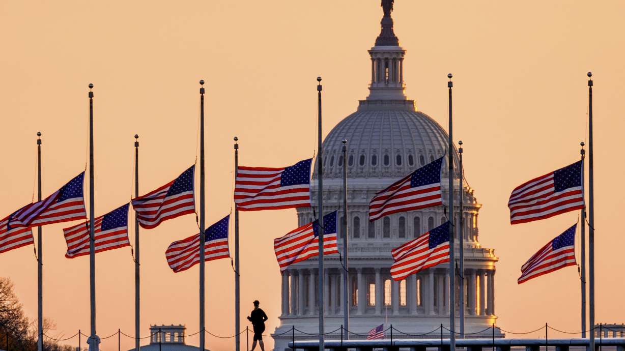 Lowered to half-staff in honor of former Senate Majority Leader Bob Dole of Kansas, flags fly in the breeze at sunrise on the National Mall with the U.S. Capitol in the background, Monday, Dec. 6, 2021, in Washington.