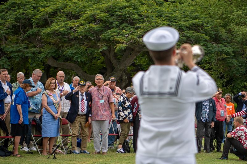 World War II veterans, along with families and friends, stand as "taps" is performed during the USS Nevada commemoration ceremony as part of the 80th Anniversary Pearl Harbor Remembrance near Honolulu, Hawaii Dec. 5.