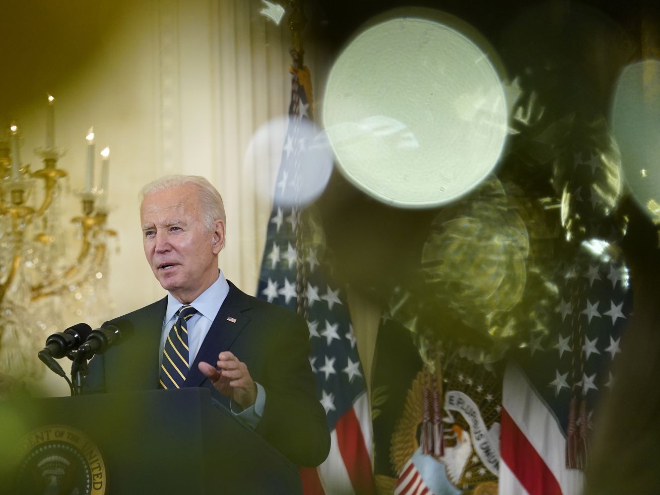 President Joe Biden, viewed through the branches of a
Christmas tree, speaks from the East Room of the White House in
Washington on Monday, Dec. 6, 2021, on his administration’s plans
to lower the costs of prescription drugs, letting Medicare
negotiate drug prices, capping how much seniors and people with
disabilities have to pay for drugs.