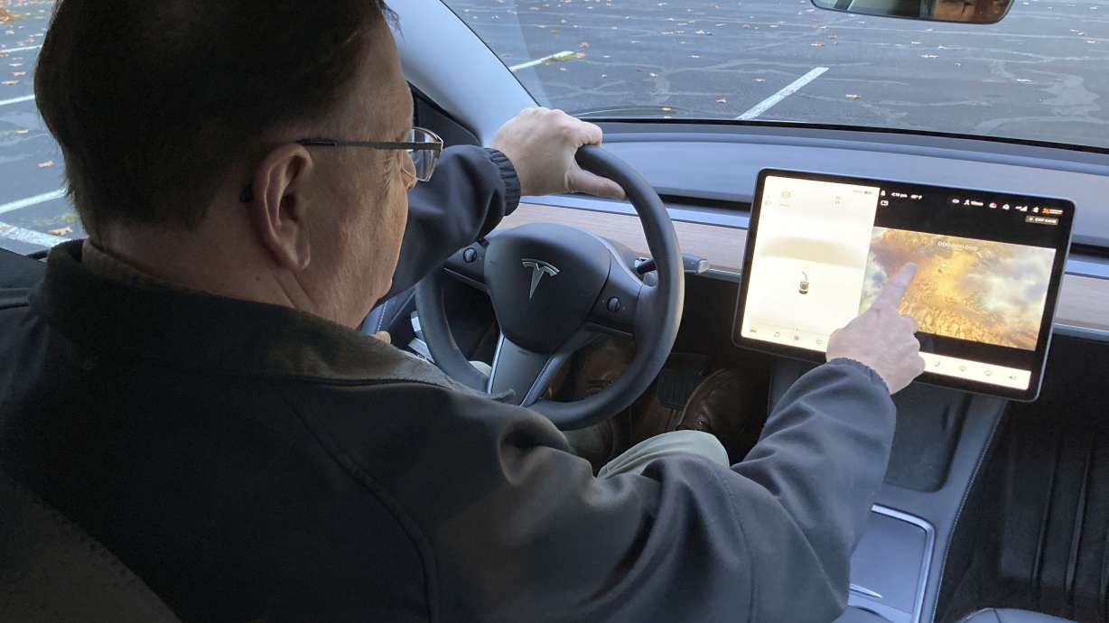 Vince Patton, a new Tesla owner, demonstrates on Wednesday, on a closed course in Portland, Ore., how he can play video games on the vehicle's console while driving. Patton, of Portland, filed a complaint with federal regulators after discovering the feature in his new car.
