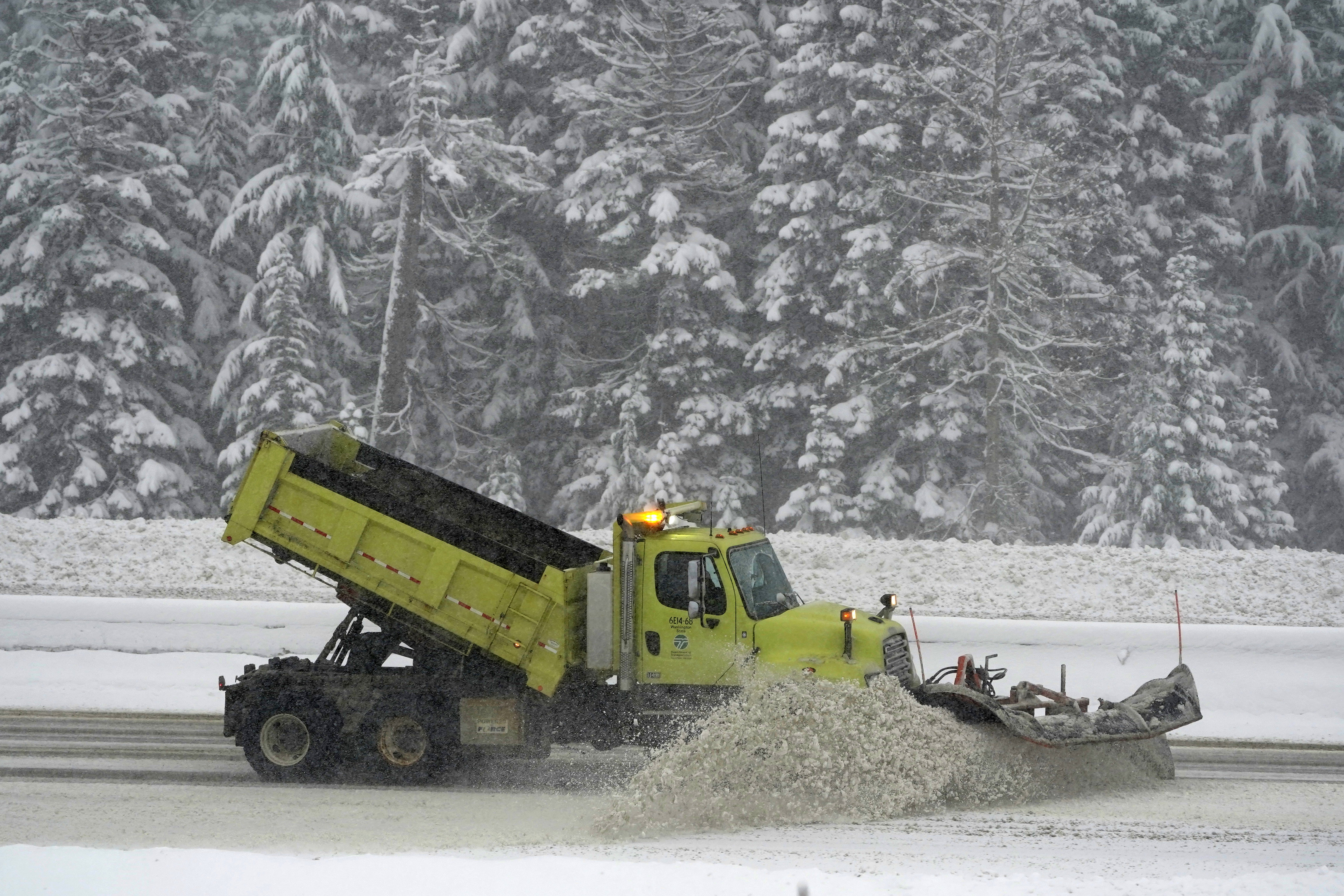 A Washington Dept. of Transportation snow plow works on a stretch of eastbound Interstate Highway 90, Thursday, as snow falls near Snoqualmie Pass in Washington state.