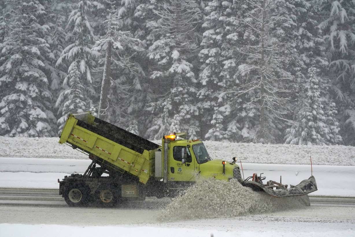 A Washington Dept. of Transportation snow plow works on a stretch of eastbound Interstate Highway 90, Thursday, as snow falls near Snoqualmie Pass in Washington state.