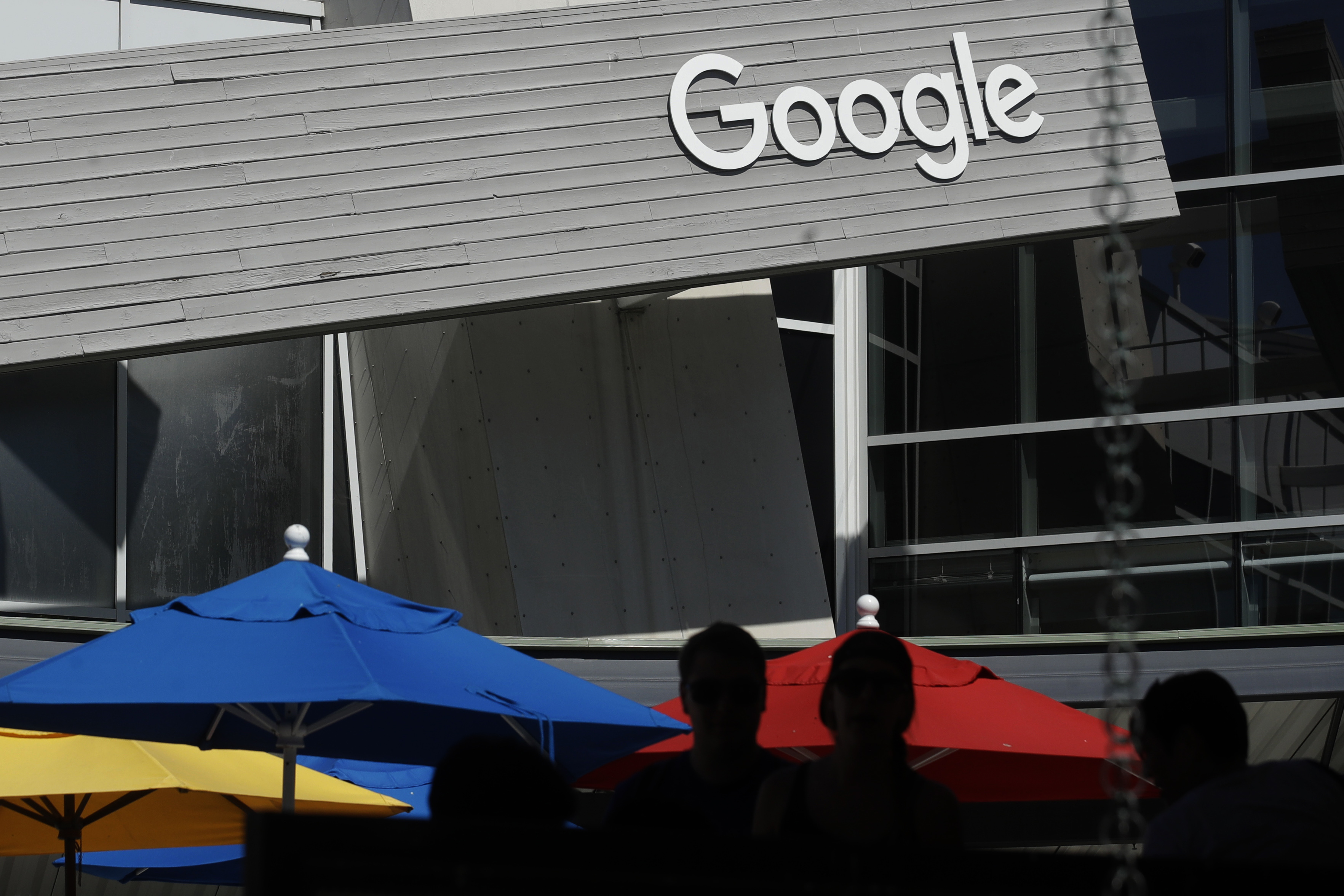 People walk by a Google sign on the company's campus in Mountain View, Calif., on Sept. 24, 2019. Omicron variant has companies rethinking return-to-office plans.