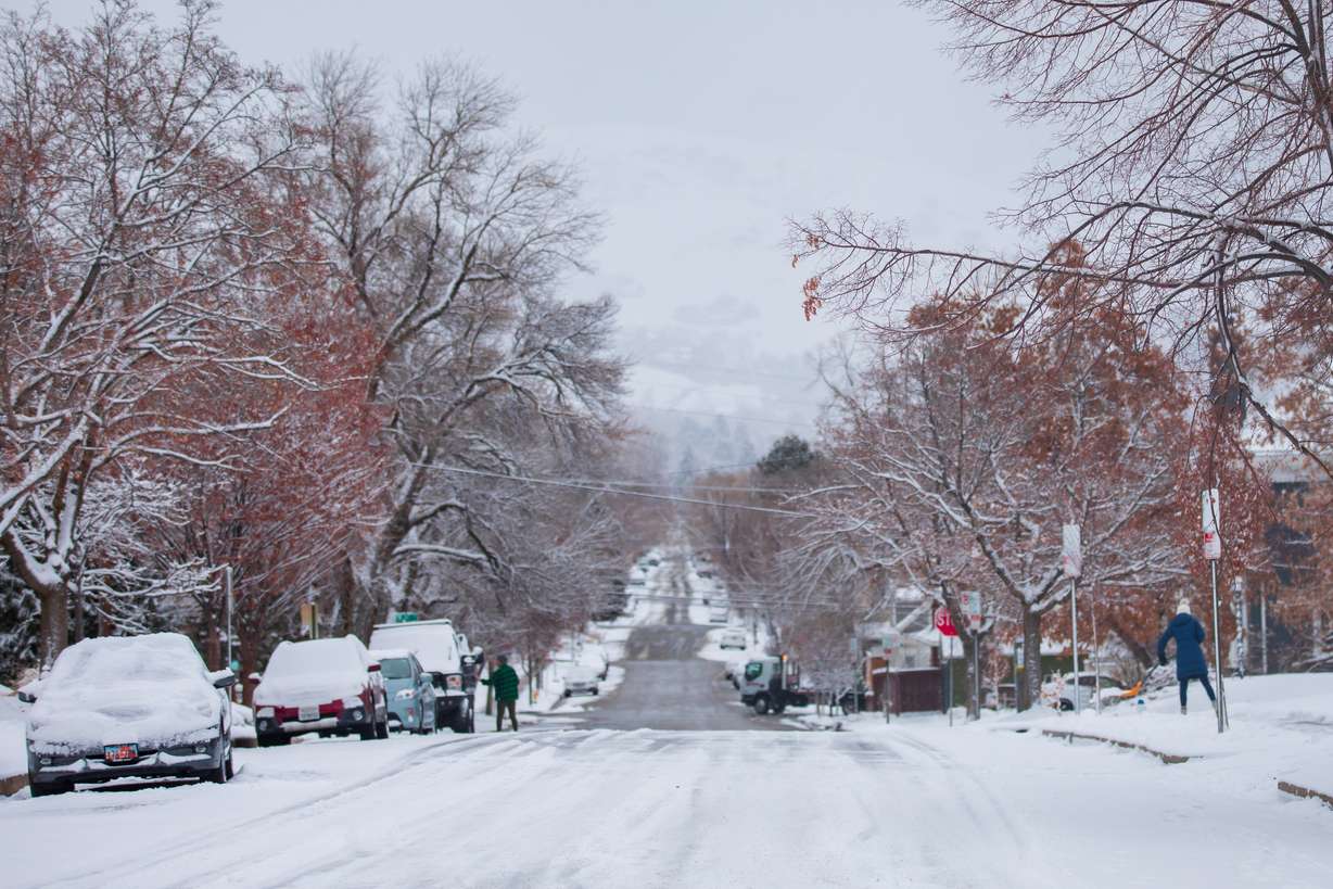 Residents clear snow from their sidewalks and cars in Salt Lake City's Avenues neighborhood Friday.
