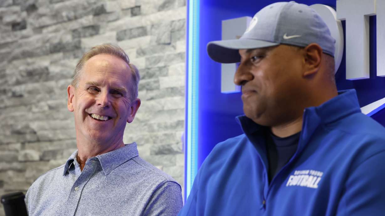 BYU athletic director Tom Holmoe, left, laughs with BYU coach Kalani Sitake after the Cougars announced a contract extension through the 2027 season, Friday, Dec. 10, 2021 in Provo.