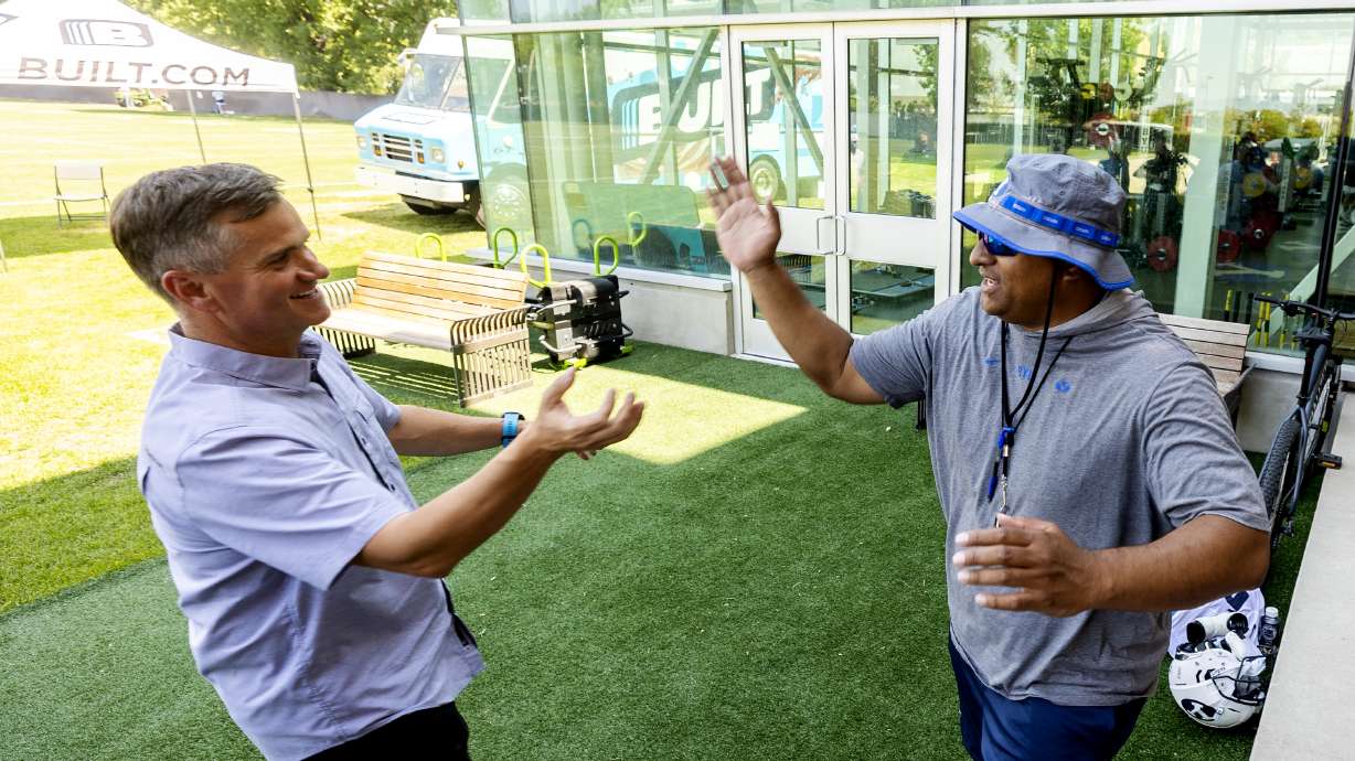 Nick Greer, co-founder of Built Brands, left, and BYU football coach Kalani Sitake greet each other during a press conference at the BYU Student Athlete Building in Provo on Friday, Aug. 13, 2021, where they discussed Built Brands’ name, image and likeness agreement with BYU.