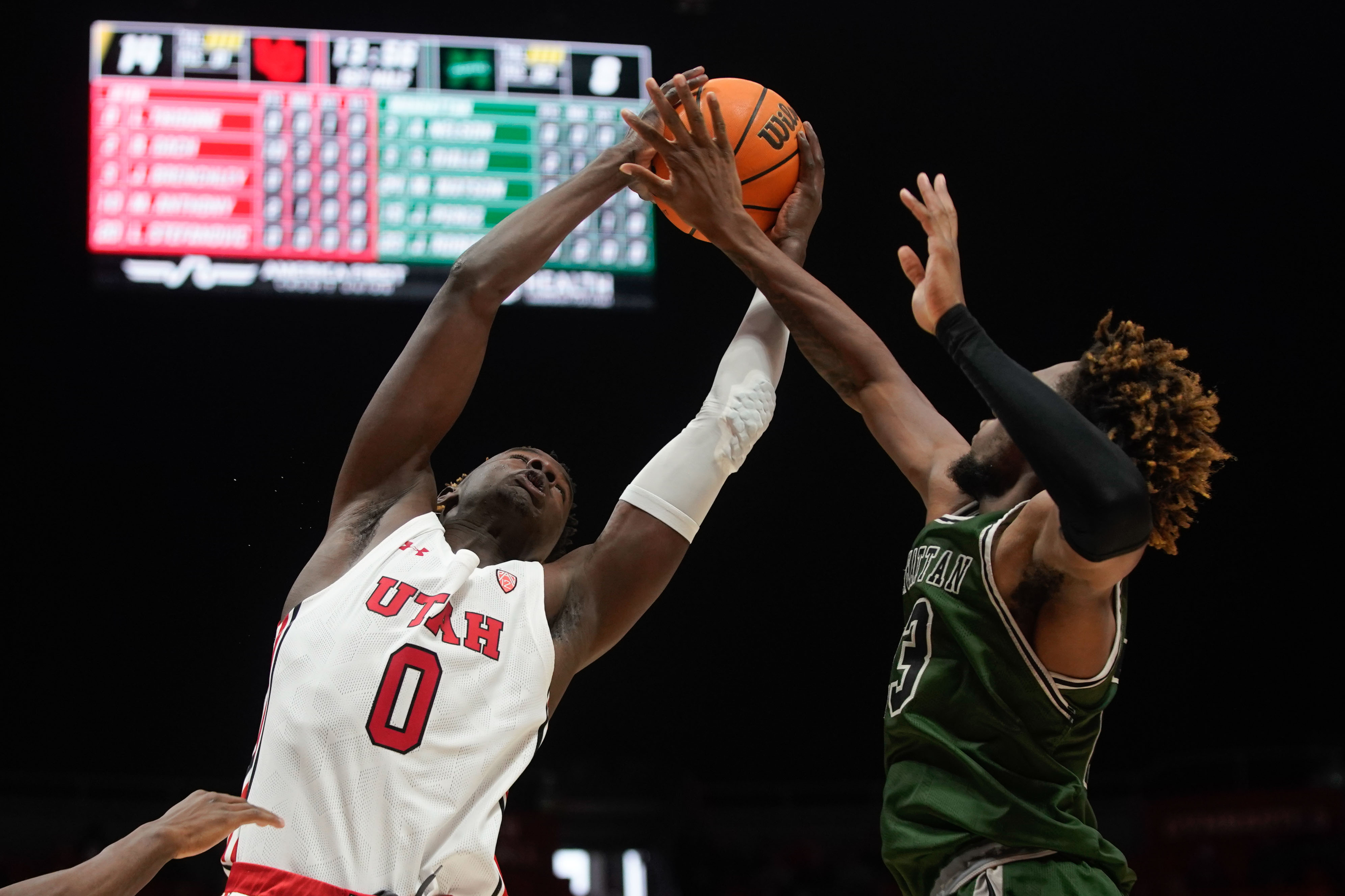 Utah center Lahat Thioune (0) and Manhattan forward Josh Roberts, right reaches to take the possession of the ball during an NCAA game at the Huntsman Center in Salt Lake City on Saturday, Dec. 11, 2021.