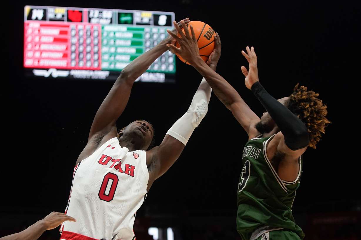 Utah center Lahat Thioune (0) and Manhattan forward Josh Roberts, right reaches to take the possession of the ball during an NCAA game at the Huntsman Center in Salt Lake City on Saturday, Dec. 11, 2021.