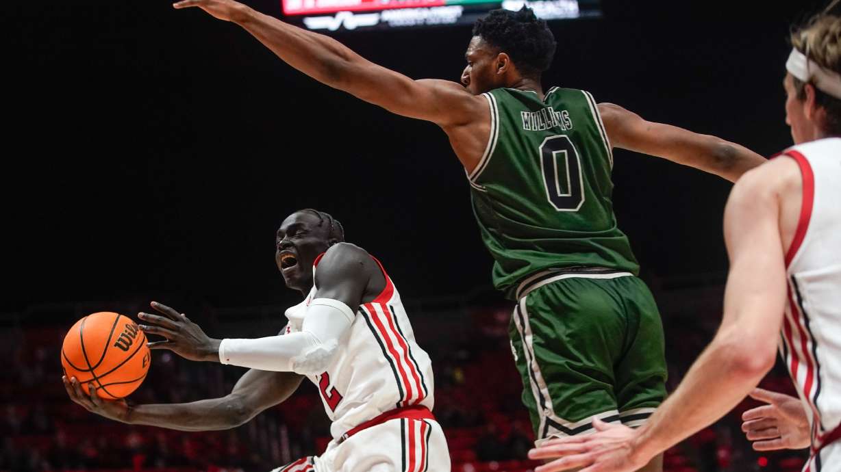 Utah center Lahat Thioune, left, goes for a shot as Manhattan forward Warren Williams jumps to block during an NCAA game at the Huntsman Center in Salt Lake City on Saturday, Dec. 11, 2021.