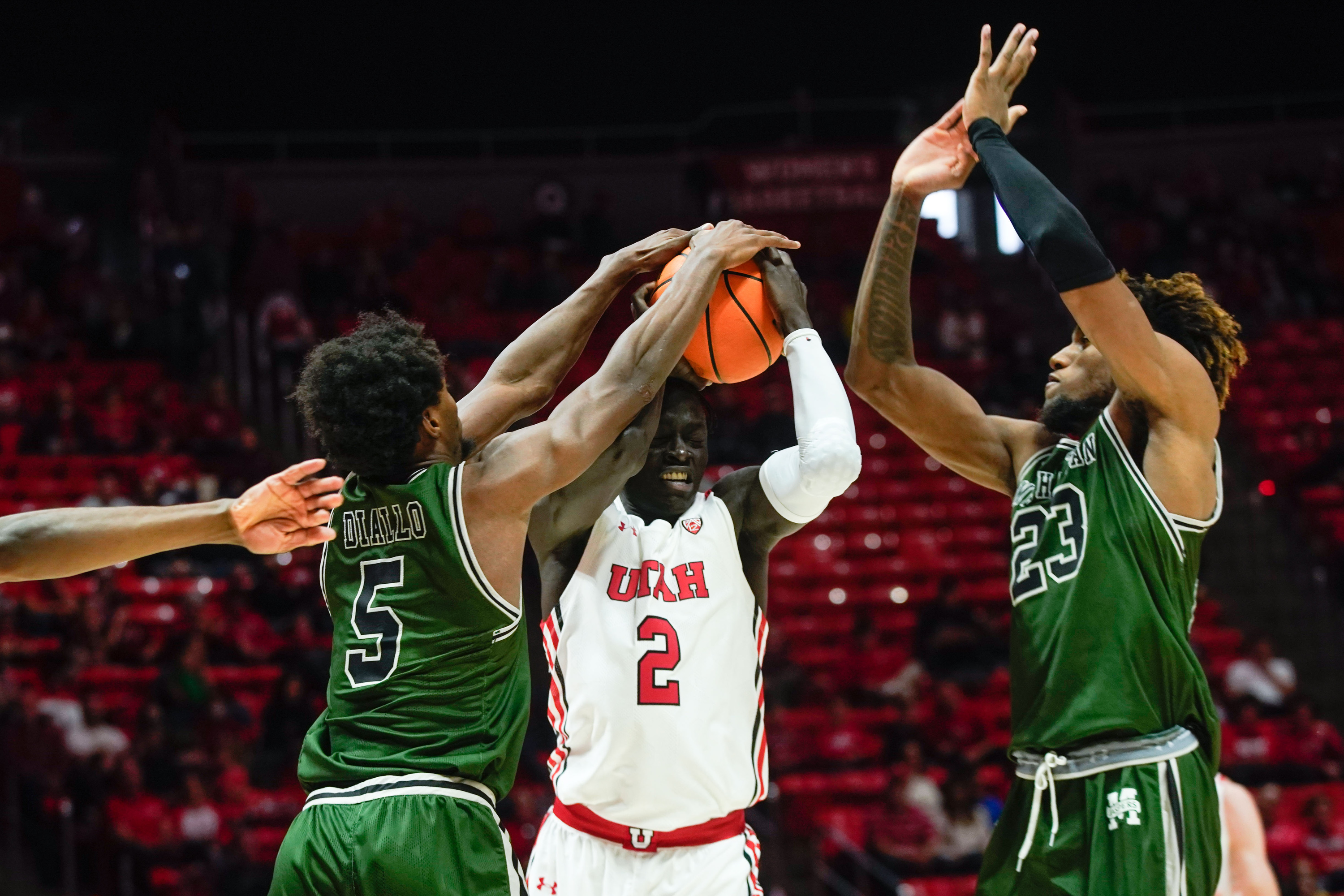Utah guard Both Gach (2), reacts while keeping the possession between Manhattan forward Samba Diallo, left and forward Josh Roberts during an NCAA game at the Huntsman Center in Salt Lake City on Saturday, Dec. 11, 2021.