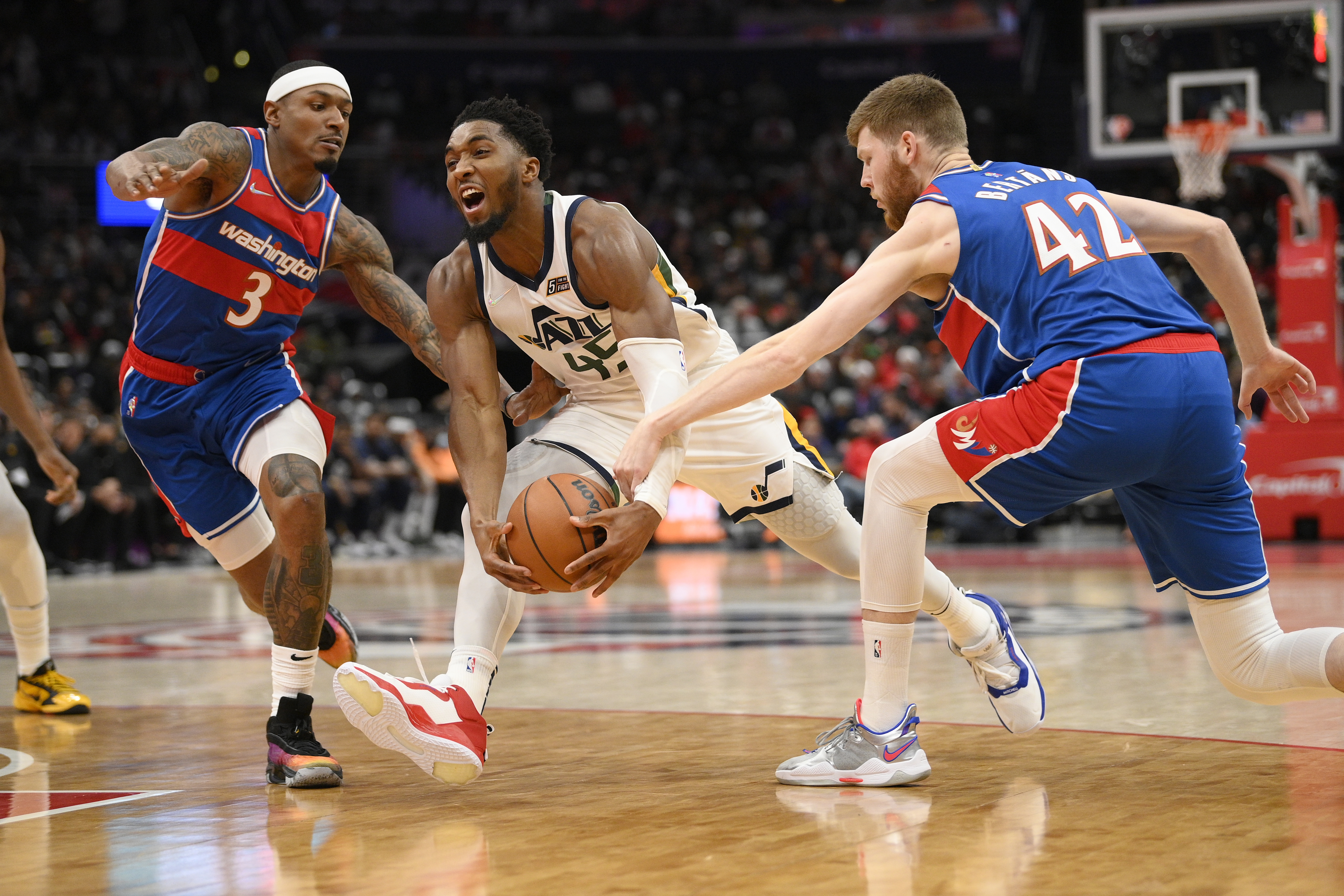 Utah Jazz guard Donovan Mitchell (45) drives to the basket against Washington Wizards guard Bradley Beal (3) and forward Davis Bertans (42) during the first half of an NBA basketball game Saturday, Dec. 11, 2021, in Washington. 