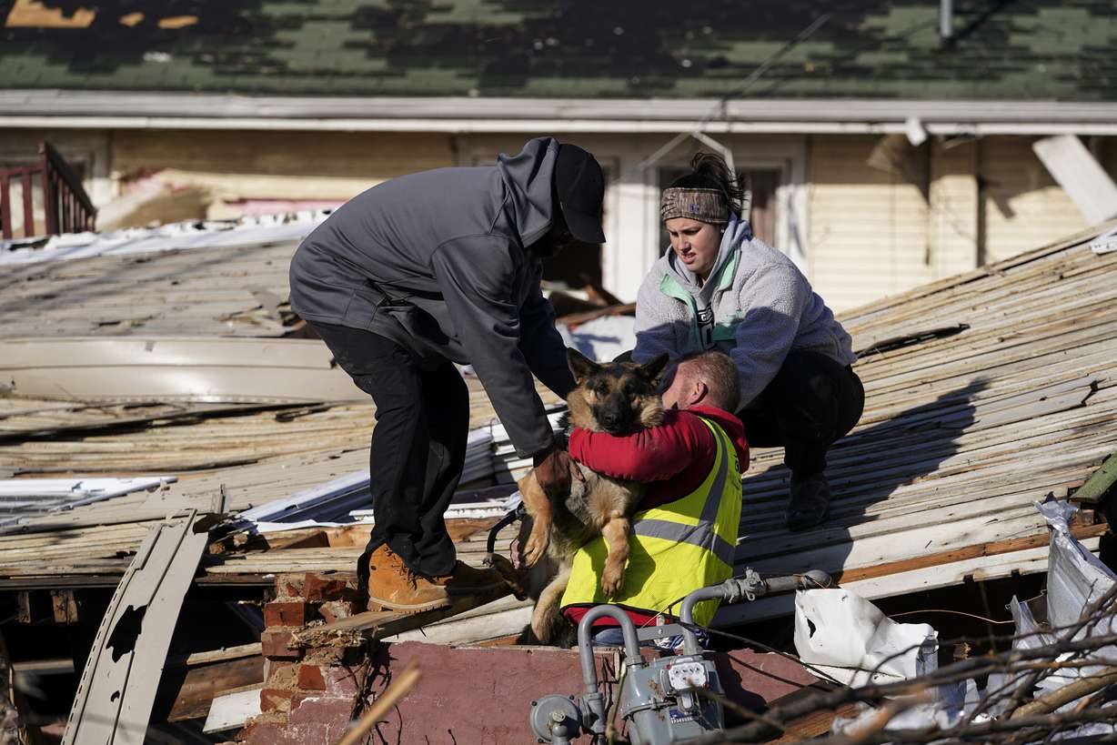 Dog owner Derrick Starks, left, Chris Buchanan, center and Niki Thompson, right, both from neighboring counties, attempt to rescue Cheyenne from a tornado-damaged home in Mayfield, Ky., on Saturday, Dec. 11, 2021. Tornadoes and severe weather caused catastrophic damage across multiple states late Friday, killing dozens of people overnight.
