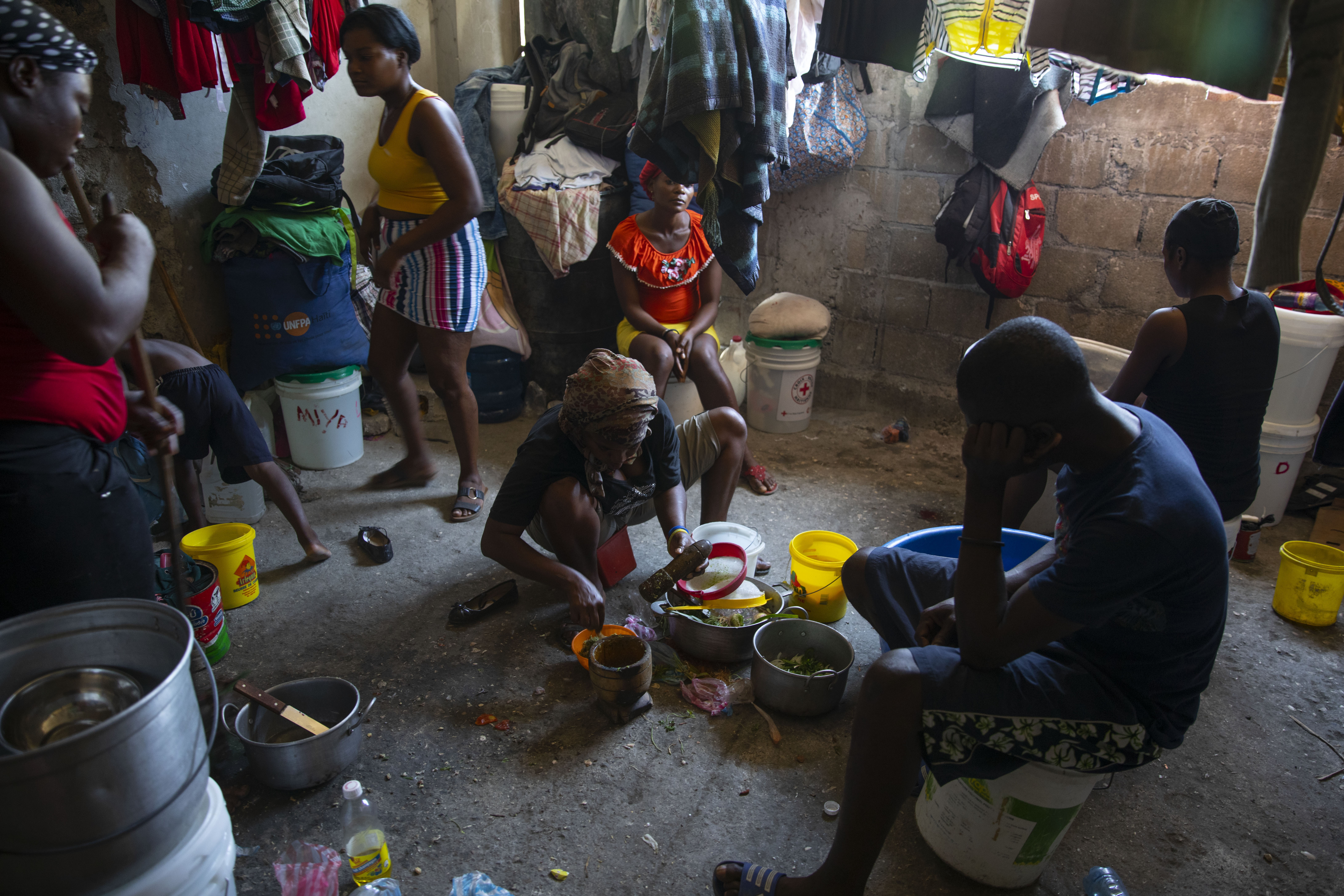 A woman prepares food at a shelter for families displaced by gang violence in Port-au-Prince, Haiti, Thursday. A spike in violence has deepened hunger and poverty in Haiti while hindering the very aid organizations combating those problems in a country whose government struggles to provide basic services. 