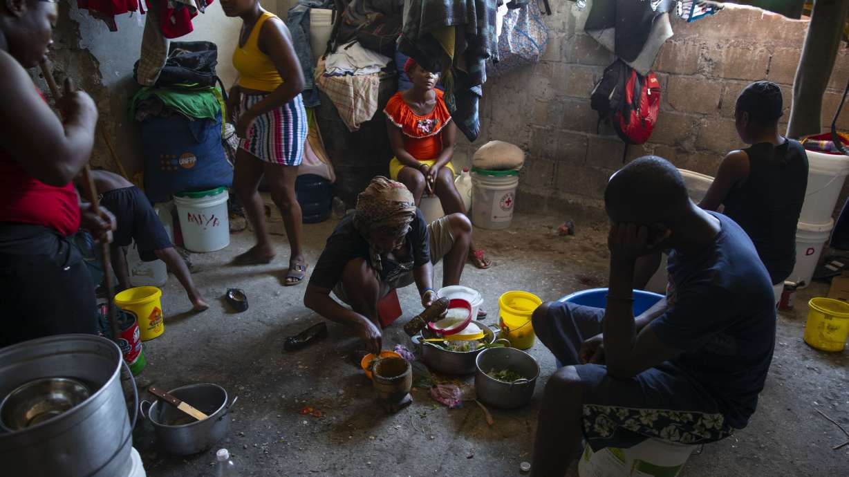 A woman prepares food at a shelter for families displaced by gang violence in Port-au-Prince, Haiti, Thursday. A spike in violence has deepened hunger and poverty in Haiti while hindering the very aid organizations combating those problems in a country whose government struggles to provide basic services.