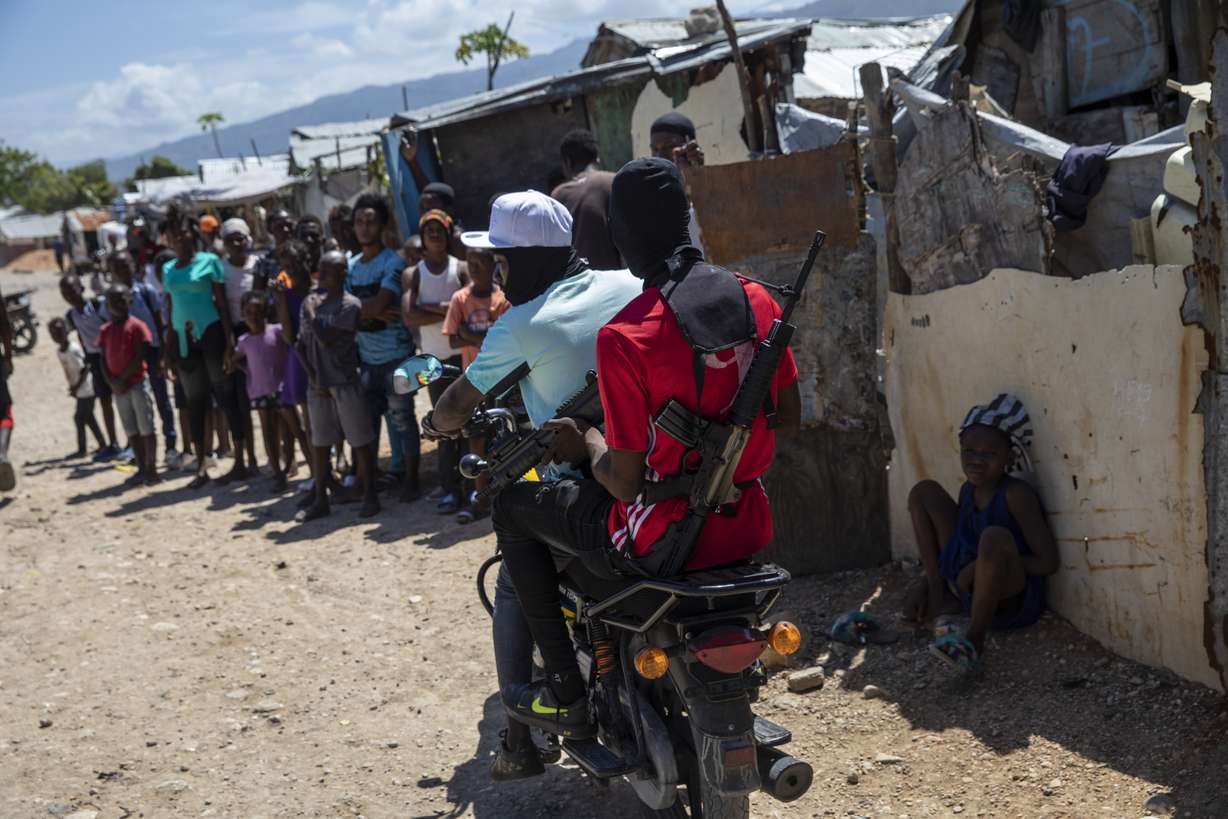 G9 coalition gang members ride a motorcycle through the Wharf Jeremy street market in Port-au-Prince, Haiti, Oct. 6. While some gangs have turned to kidnapping, like those who captured 17 missionaries and their relatives, Jimmy Cherizier, aka Barbecue, a former policeman who leads the G9 gang coalition, has taken control of the port district, gaining a stranglehold on the country's economy.