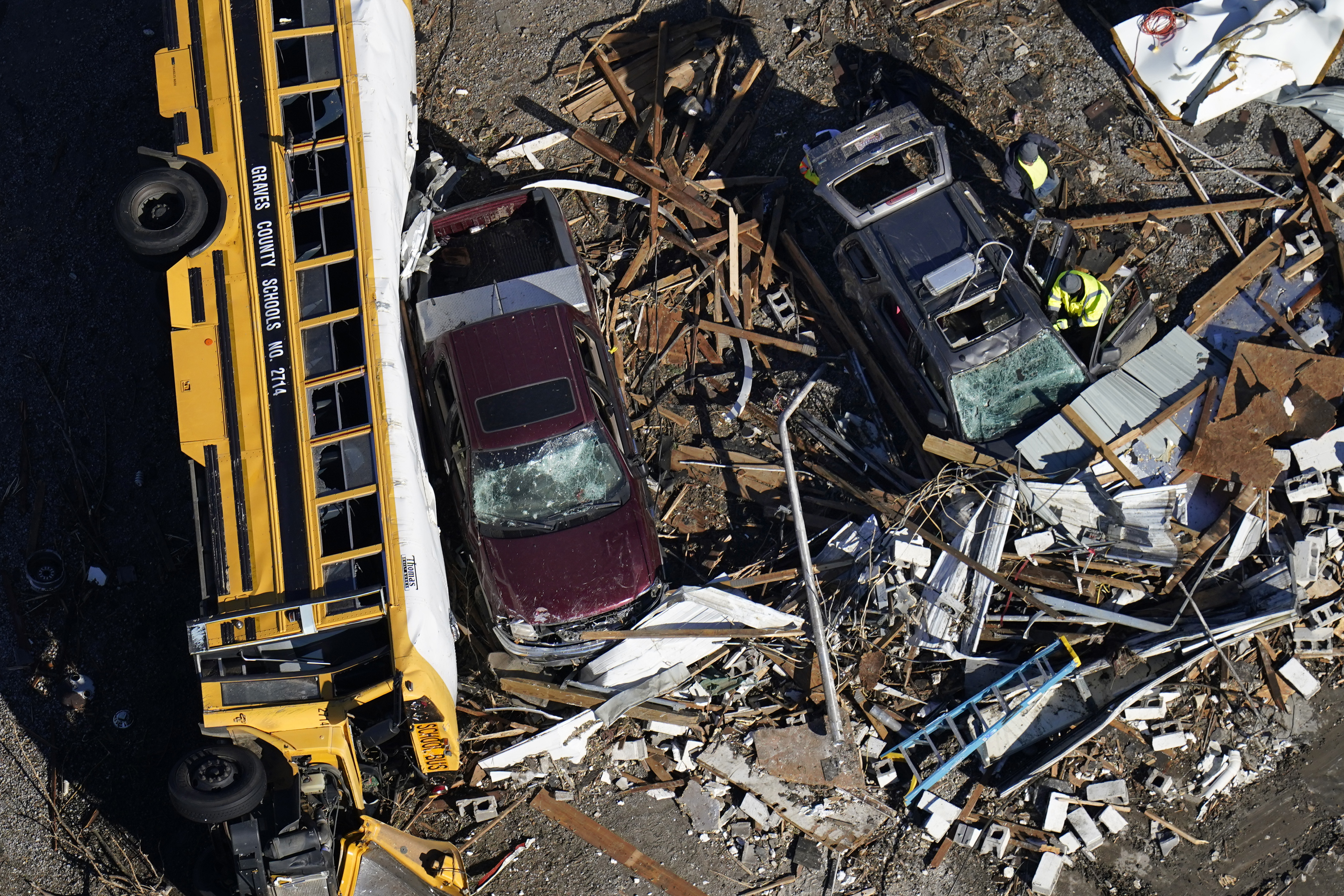 In this aerial photo, responders sift through debris near an overturned school bus in the aftermath of tornadoes that tore through the region, in Mayfield, Ky., Sunday.