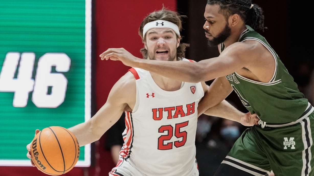 Utah guard Rollie Worster (25) goes past Manhattan guard Ant Nelson during an NCAA game at the Huntsman Center in Salt Lake City on Saturday, Dec. 11, 2021.