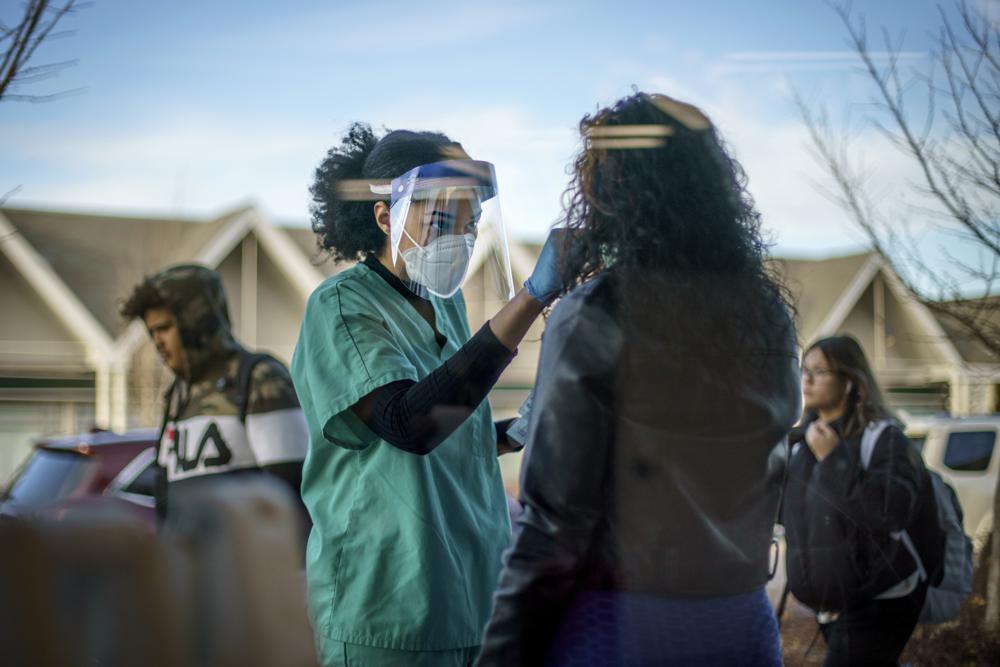 Maya Goode, a COVID-19 technician, performs a test on Jessica Sanchez outside Asthenis Pharmacy in Providence, R.I., on Tuesday. As the omicron variant sparks worldwide fears of renewed virus outbreaks, fewer Americans say they are regularly wearing masks or avoiding crowds now compared with the beginning of the year.
