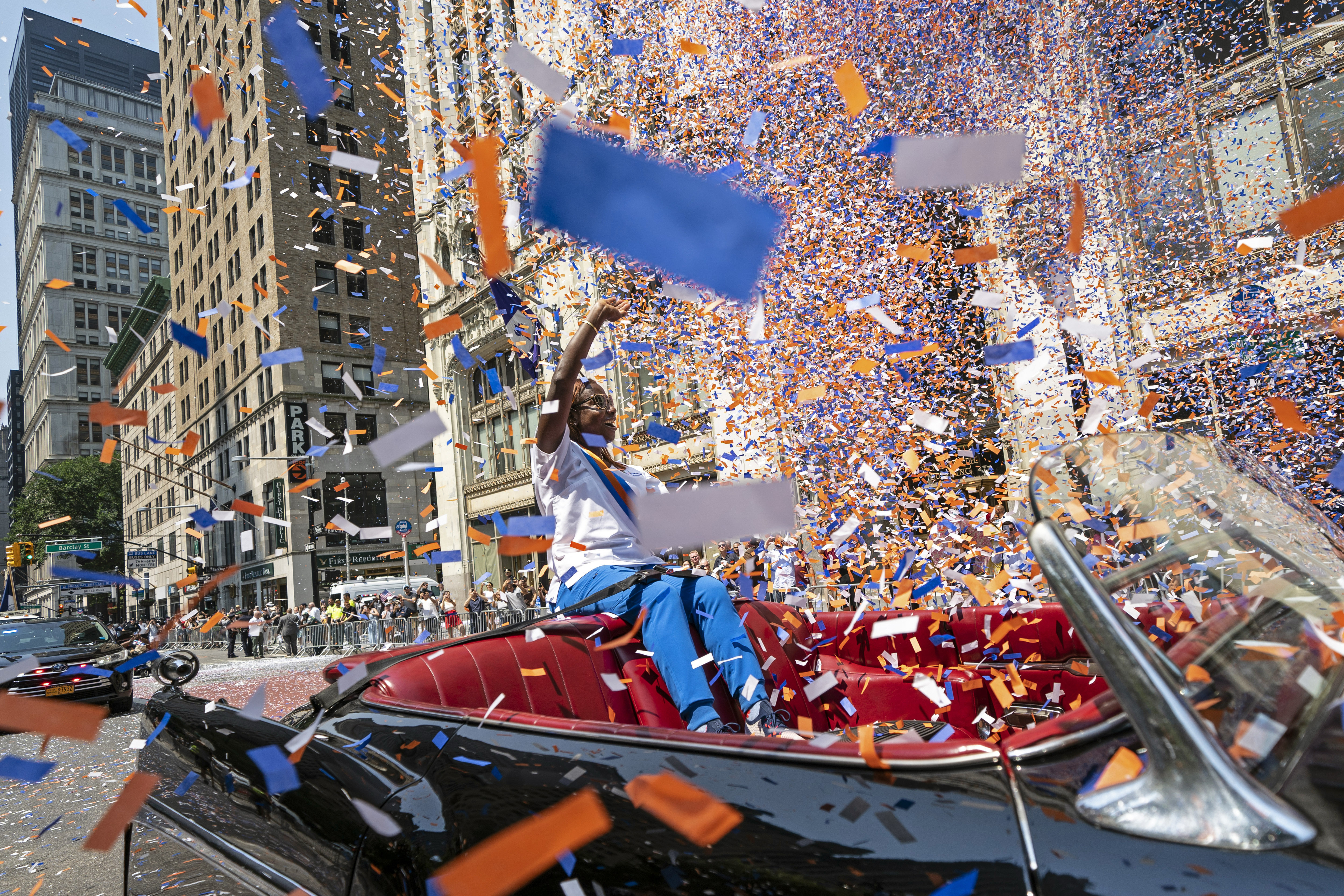 Grand marshal Sandra Lindsay, a health care worker who was the first person in the country to get a COVID-19 vaccine shot, waves to spectators as she leads marchers through the Financial District as confetti falls during a parade honoring essential workers for their efforts in getting New York City through the COVID-19 pandemic, July 7, in New York.