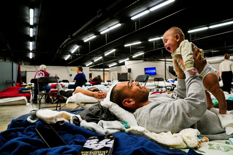 Anthony Vasquez, 42, plays with his 4 month-old son Michael inside a makeshift shelter which houses people who lost their homes after tornadoes ripped through several states in Wingo, Kentucky, Monday.