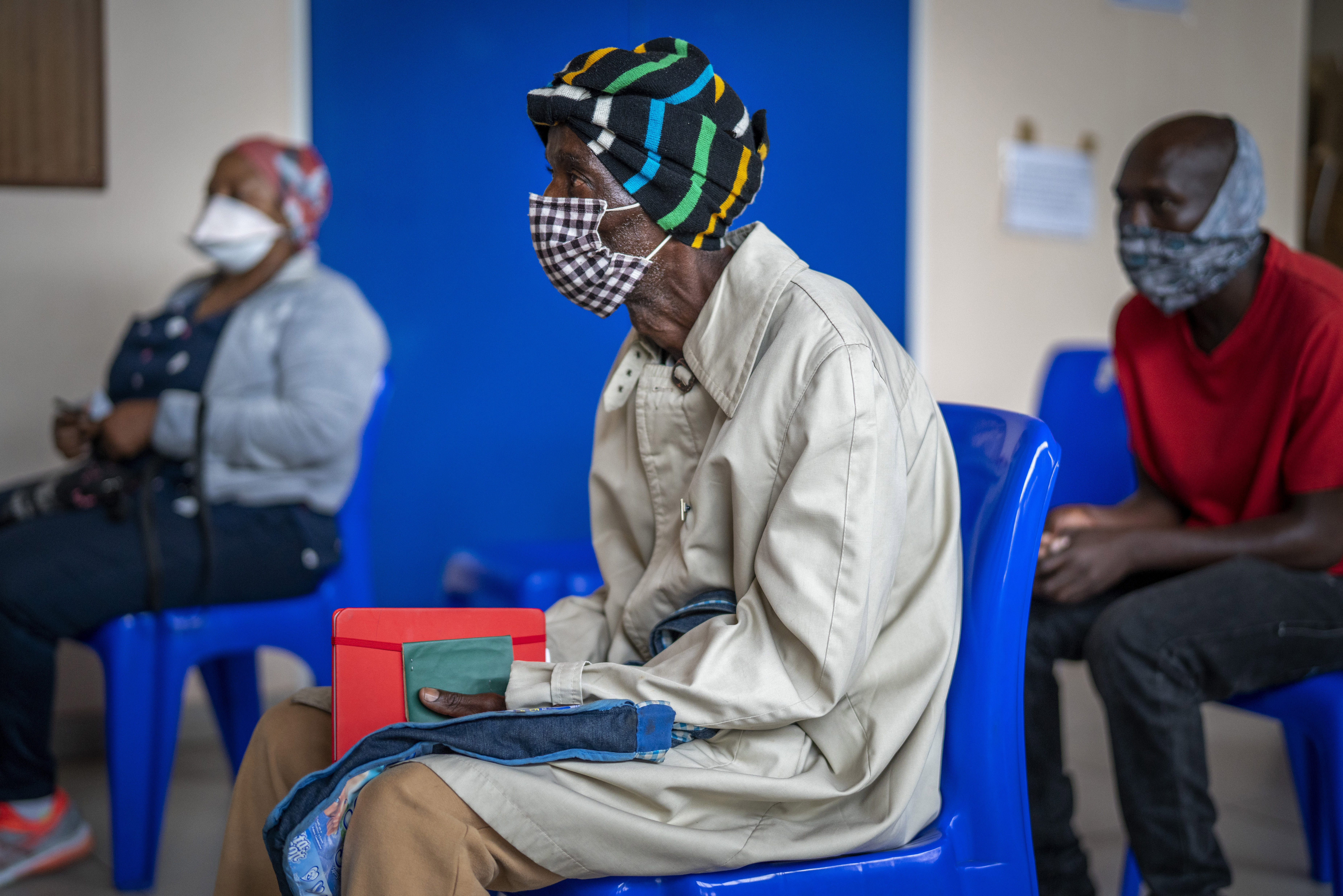 People wait for COVID-19 vaccination at Soweto's Baragwanath hospital in South Africa Monday. In general, the new omicron cases have resulted in milder cases, with fewer hospitalizations and less severe cases requiring oxygen or intensive care.