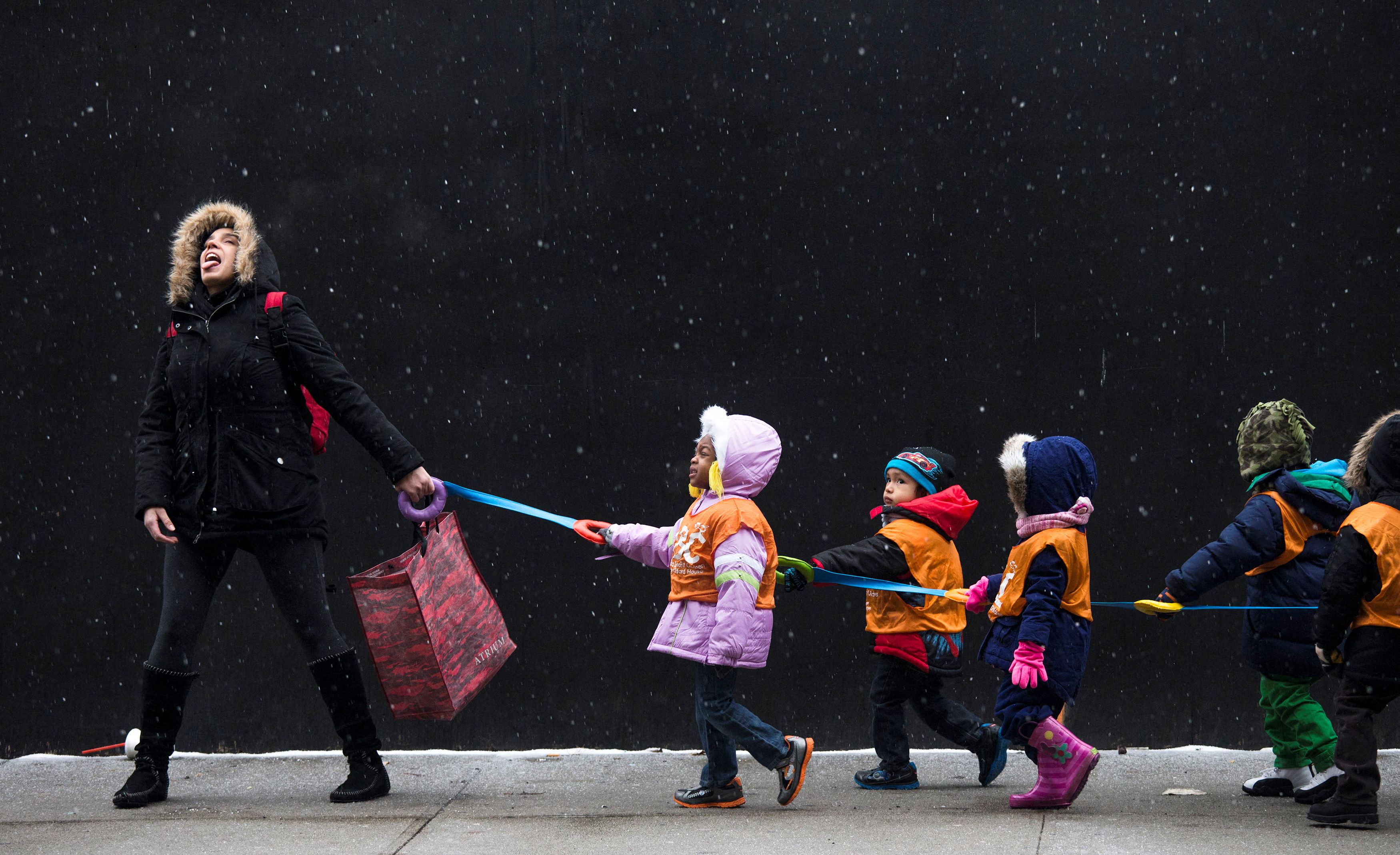 A schoolteacher, who wished to stay unidentified, attempts to catch snowflakes while leading her students to a library from school in the Harlem neighborhood, located in the Manhattan borough of New York on January 10, 2014.  