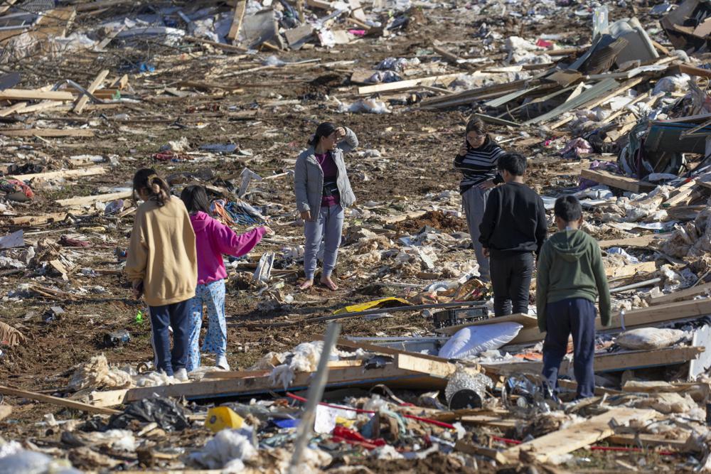 Vung Nuam, center, looks through the remains of her home Tuesday in Bowling Green, Ky.