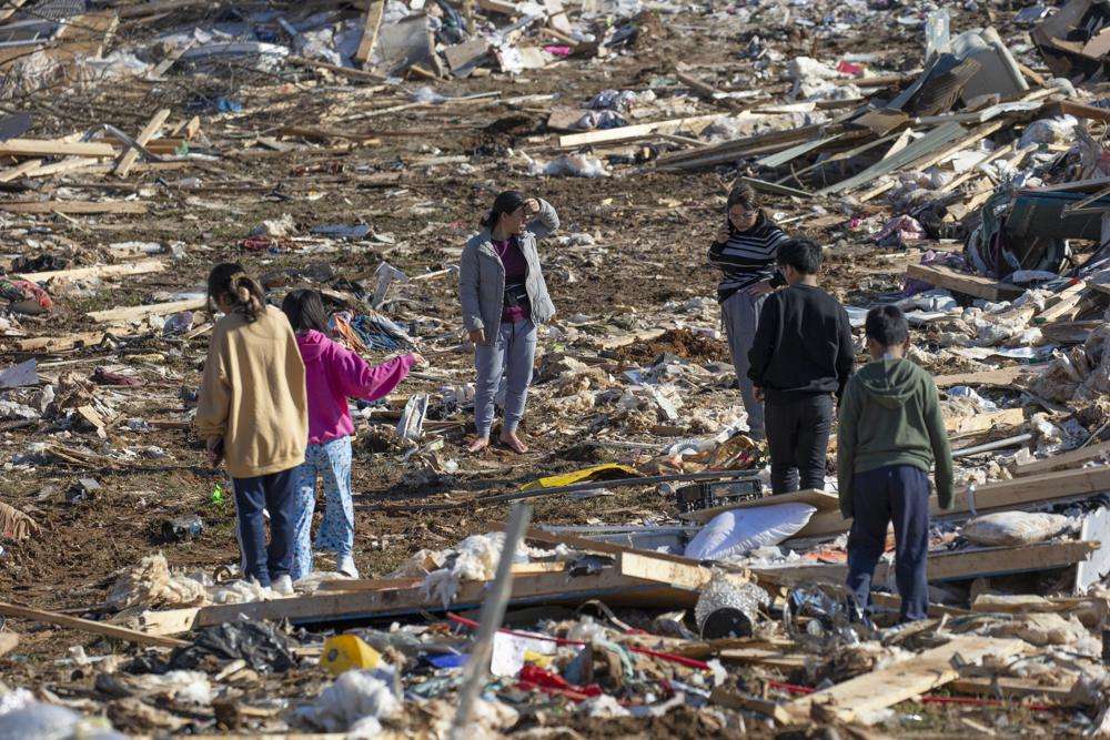 Vung Nuam, center, looks through the remains of her home Tuesday in Bowling Green, Ky.