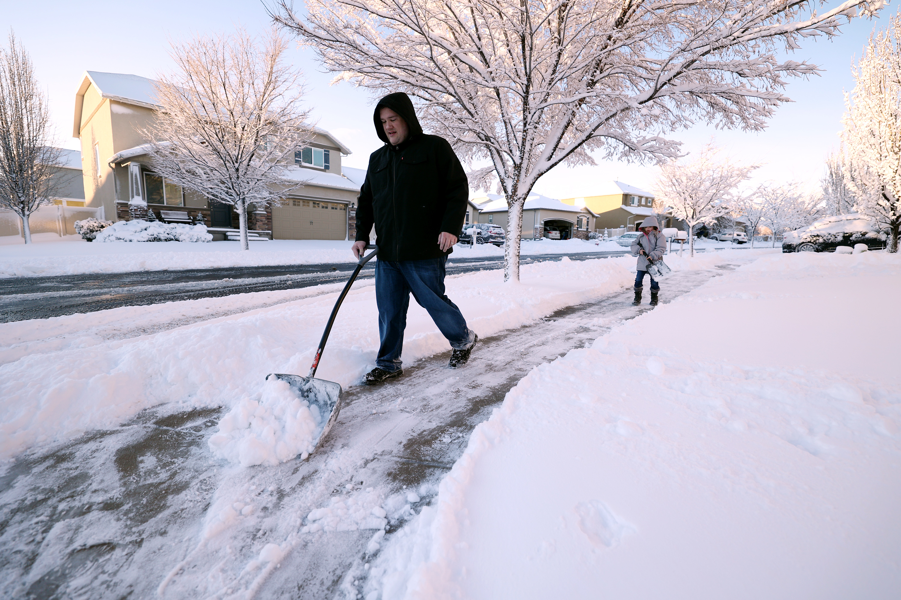 Carl Wayman gets help from his daughter, Tori Wayman, in removing snow from the sidewalk in front of their home in Herriman on Wednesday. Snow returned to northern Utah Thursday with a smaller storm than one earlier this week.
