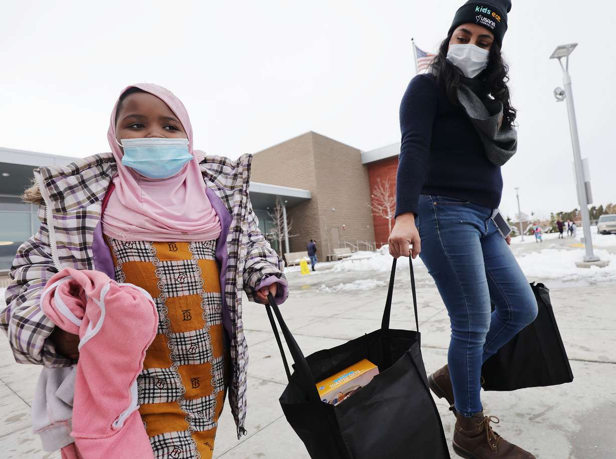 Meadowlark Elementary student Suldana Hussein, left, carries a food bag with the help of Laura Chamorro at the school in Salt Lake City on Thursday. USANA’s management team delivered 385 two-week food bags for elementary students who will be out of school for the holiday break.