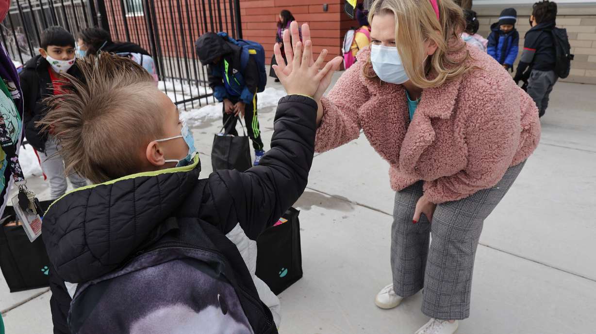 Meadowlark Elementary student Owen Currier, left, high-fives Amy Haran after she gave him a food bag at the school in Salt Lake City on Thursday, Dec. 16. USANA’s management team delivered 385 two-week food bags for elementary students who will be out of school for the holiday break.