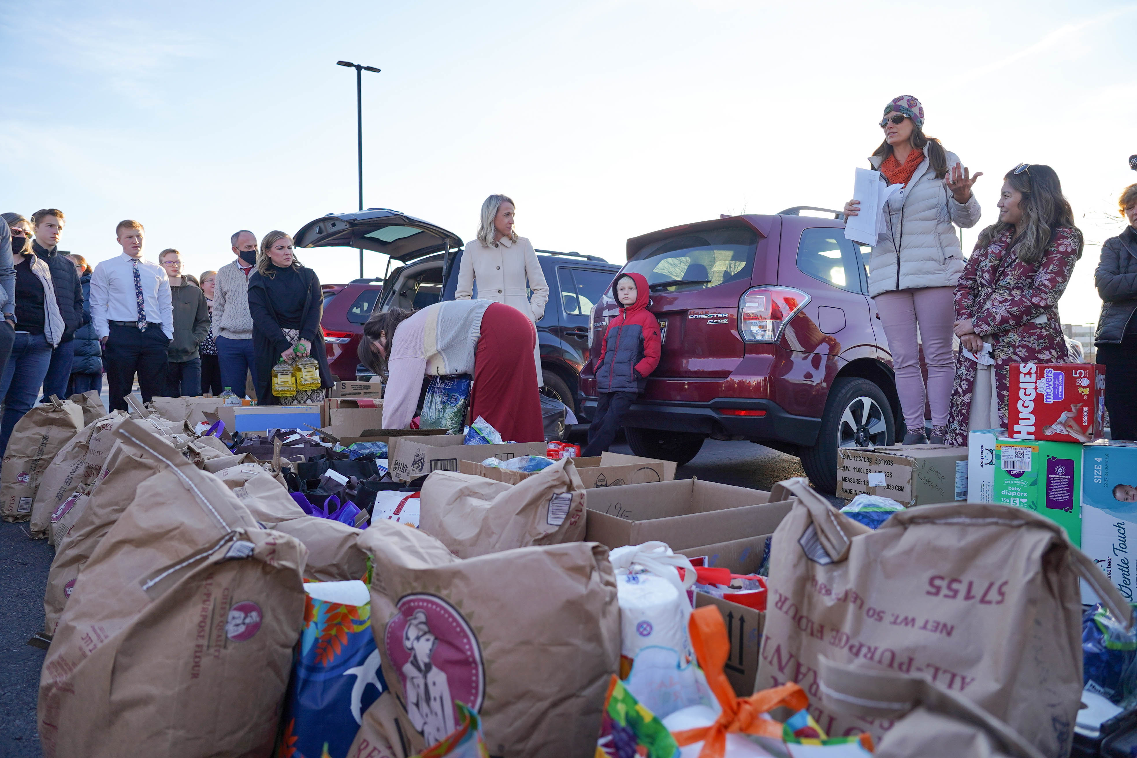 Jennifer Hua and Nazifa Rajabi address a group of volunteers in a shopping center parking lot in Midvale. They’re packing boxes to deliver to newly arrived Afghan families.