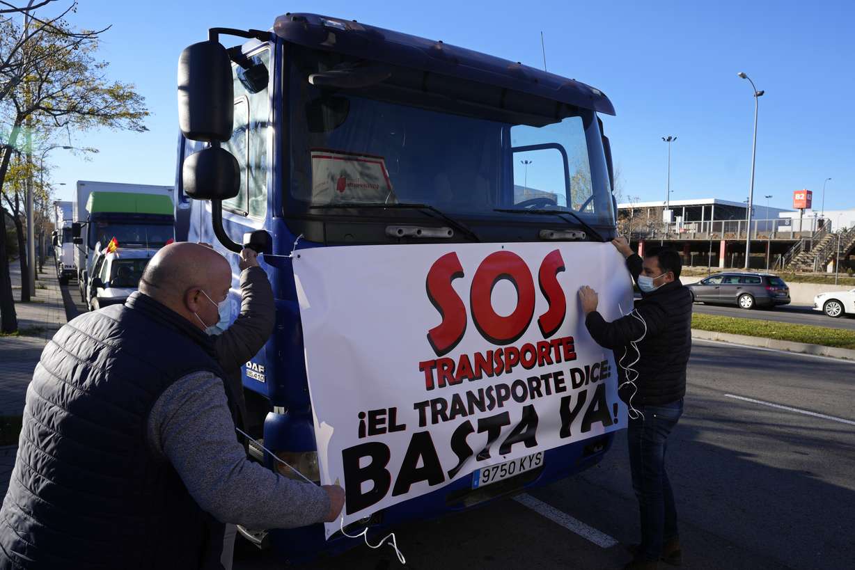 Truckers ties a banner reading 'SOS, Transport. 'That's enough' to a truck before driving slowly during a protest though Madrid, Spain, Wednesday, Dec. 15, 2021. Governments worldwide are facing protests, work stoppages or other political pressure to take action against soaring inflation. Spanish truck drivers ratcheted up the pressure by vowing a walkout days before Christmas and won relief on diesel prices, while Turkish citizens are protesting the government’s unorthodox economic policies that have worsened surging inflation and made it a struggle to buy food and other goods.