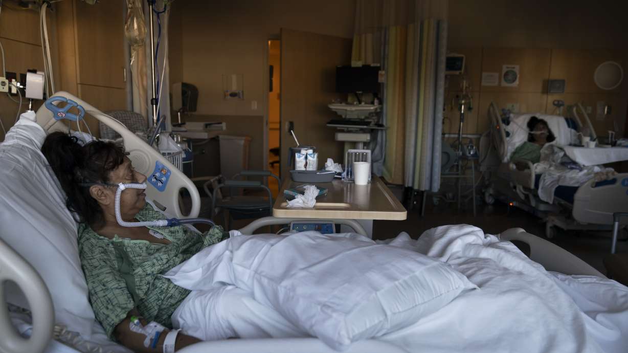 Natalie Balli, 71, and her twin sister, Linda Calderon, background right, watch TV as they rest in their beds in a COVID-19 unit at Providence Holy Cross Medical Center in Los Angeles, on Dec. 17. The sisters were admitted to the hospital on the same day, a few days after their Thanksgiving gathering.