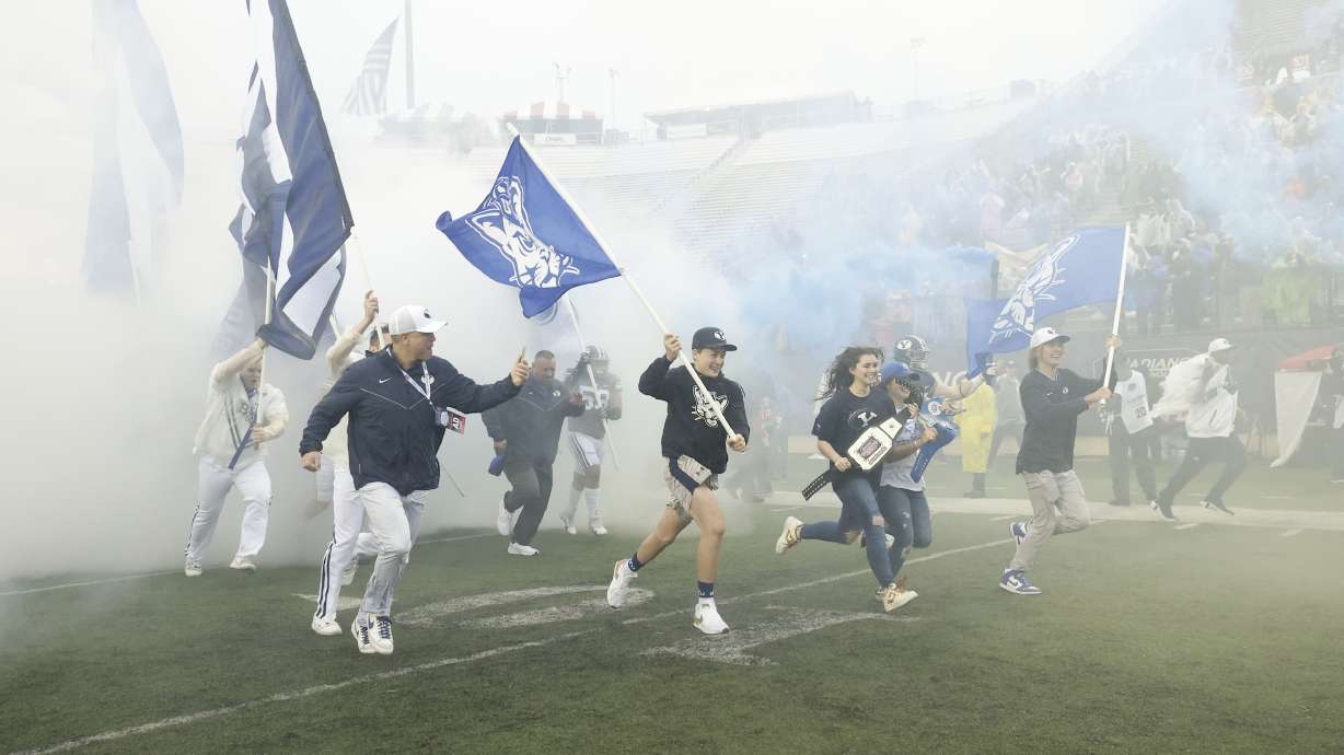 The four oldest children of longtime BYU fan Nathan Peterson, who was recently diagnosed with a brain tumor, run out the flag before the Cougars' bowl game against UAB in the Independence Bowl, Saturday, Dec. 18, 2021 in Shreveport, La.