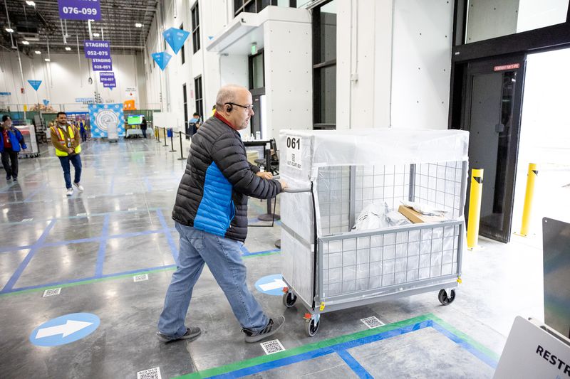 Mike Knudsen, an Amazon Flex driver, moves a cart of
packages to his car at Amazon’s new sub same-day fulfillment
facility, dubbed SUT1, in Salt Lake City on Dec. 9.
Once the facility is fully ramped up in February, it will
facilitate deliveries in Salt Lake City and surrounding areas
within five hours of ordering.