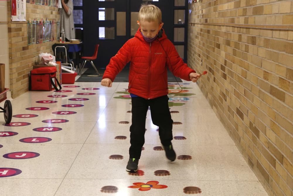 A kindergartener steps on paw print stickers in the hallway at the elementary school in Paw Paw, Michigan on Dec. 2. The task was intended to help him get past a hard start to the day. He smiled, exclaimed "All done!" when he finished and happily returned to class.