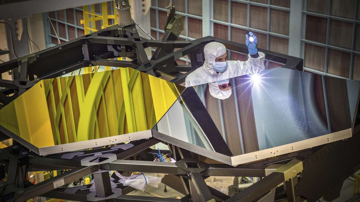James Webb Space Telescope optical engineer Larkin Carey examines two test mirror segments on a prototype at the Goddard Space Flight Center's giant clean room in Greenbelt, Md, on Sept. 29, 2014.