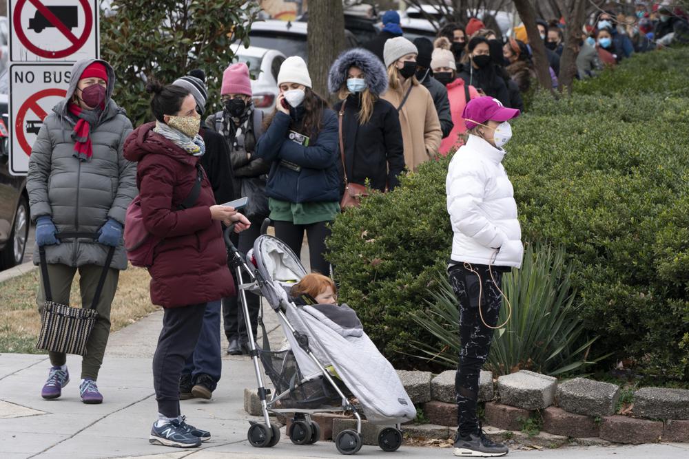 People stand in a line spanning several blocks for COVID-19 testing, Tuesday at a Curative testing kiosk outside an elementary school in northwest Washington.