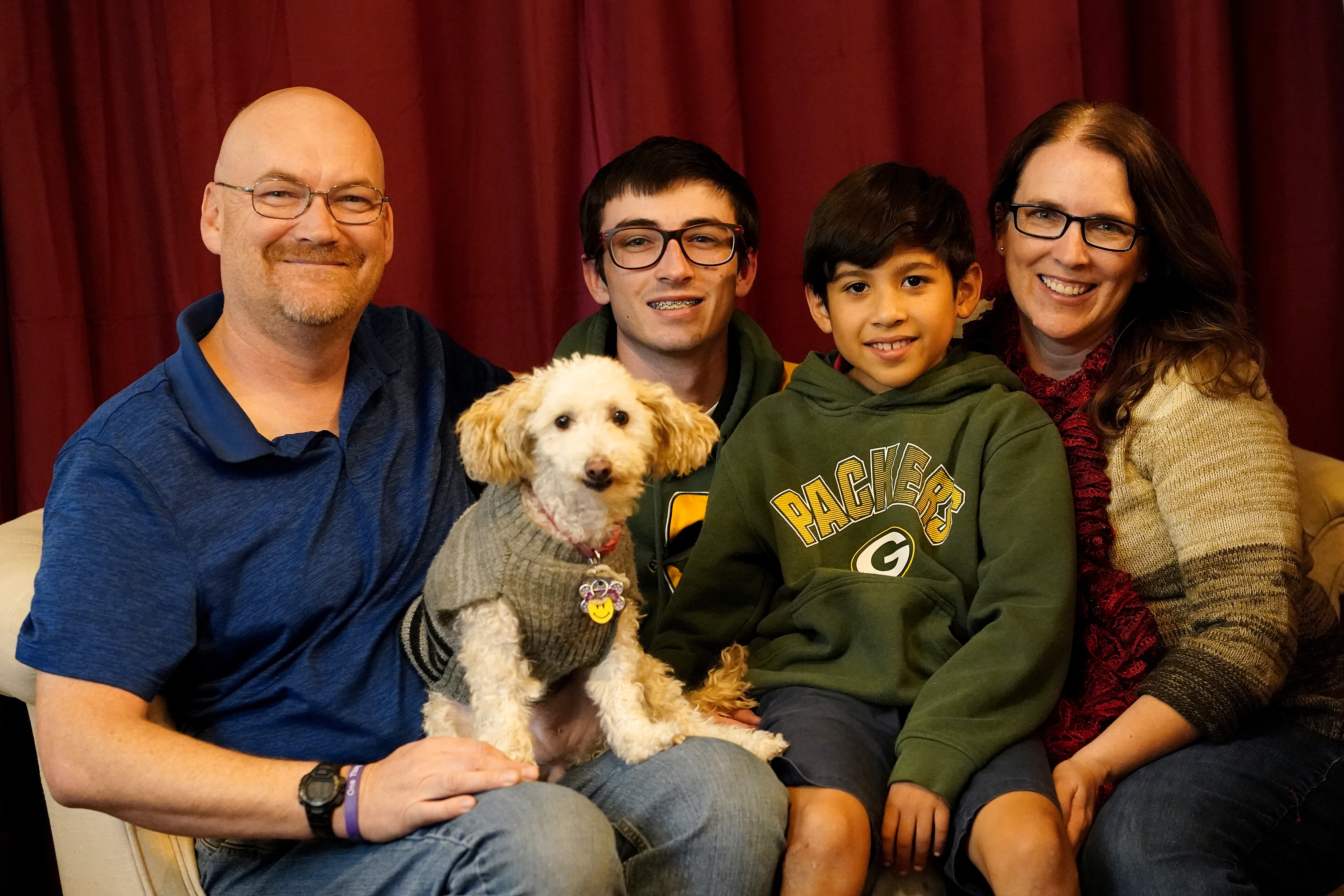 Michael Olson, from left, Paul Olson, 18, Porter Olson, 10, and Nicole Olson sit for a family photo with their dog named "Dotty"at their home, Dec. 17, in Phoenix. Porter was relinquished at birth through what's known as a safe haven law.