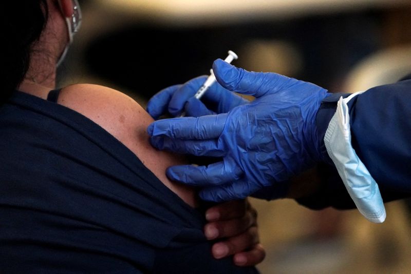 A Los Angeles County Department of Public Health worker administers a dose of a COVID-19 vaccine at a pop-up clinic at Tom Bradley International Terminal at Los Angeles International Airport on Wednesday. The Supreme Court has agreed to take up disputes over Biden's vaccine mandates.