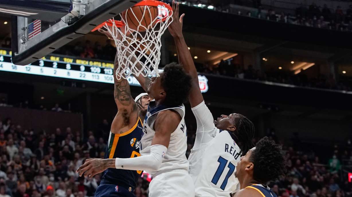 Utah Jazz guard Jordan Clarkson, left, dunks the ball past Minnesota Timberwolves defenders during an NBA game at Vivint Arena in Salt Lake City on Thursday, Dec. 23, 2021.