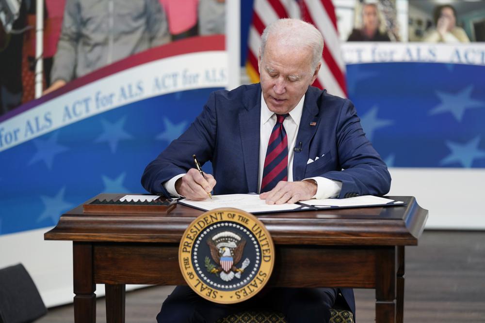 President Joe Biden signs the "Accelerating Access to Critical Therapies for ALS Act" into law during a ceremony in the South Court Auditorium on the White House campus in Washington, Thursday. On Friday, the White House announced it would lift a travel ban from eight African countries.