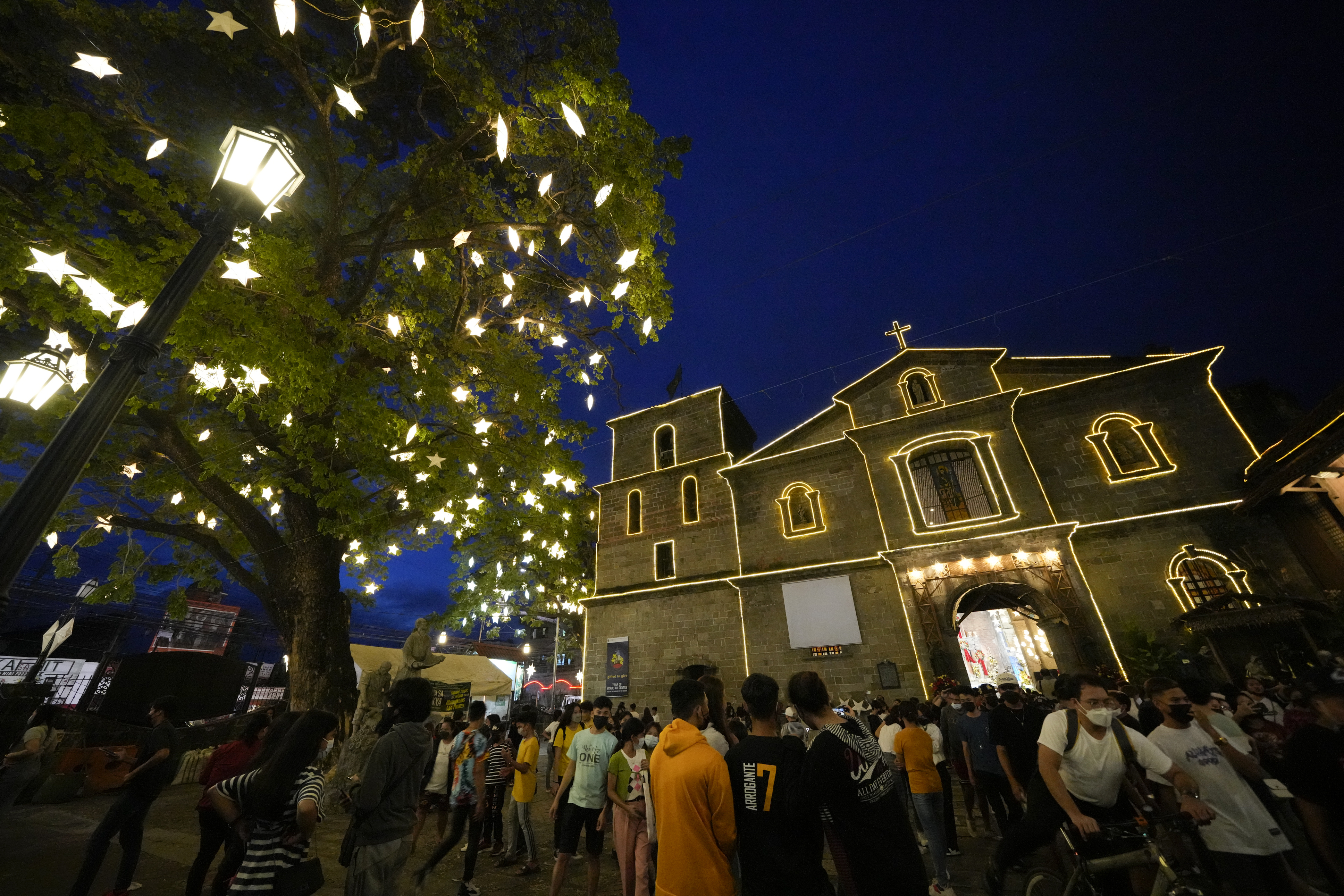 Residents wearing face masks as a safety measure to curb the spread of the coronavirus walks outside the St. Joseph Parish Church after attending the first of nine daily dawn masses before Christmas day in suburban Las Pinas city, the Philippines on Thursday, Dec. 16.