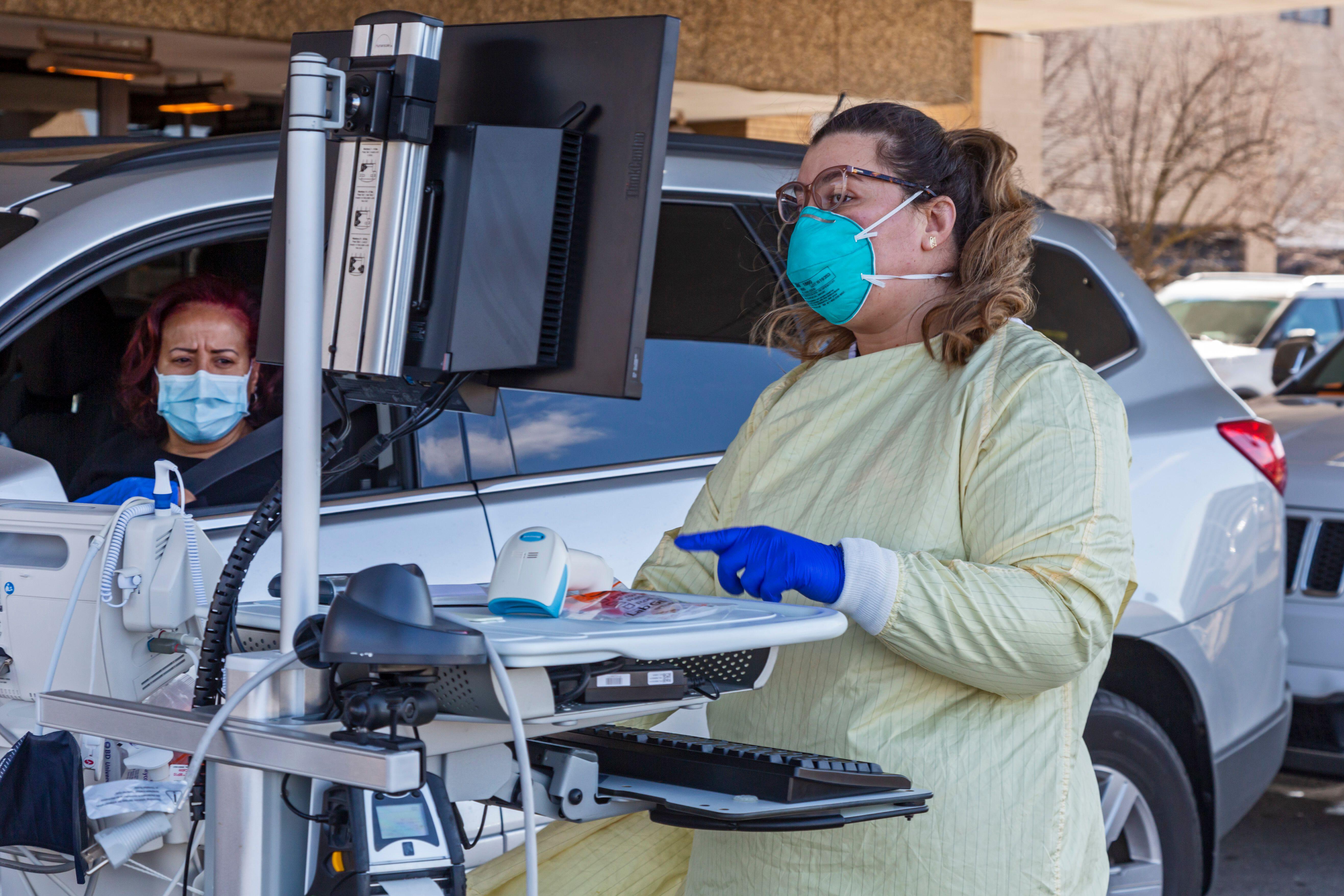 A health worker conducts drive-though testing for the COVID-19 virus outside Beaumont Hospital in Royal Oak, Mich., March 17, 2020