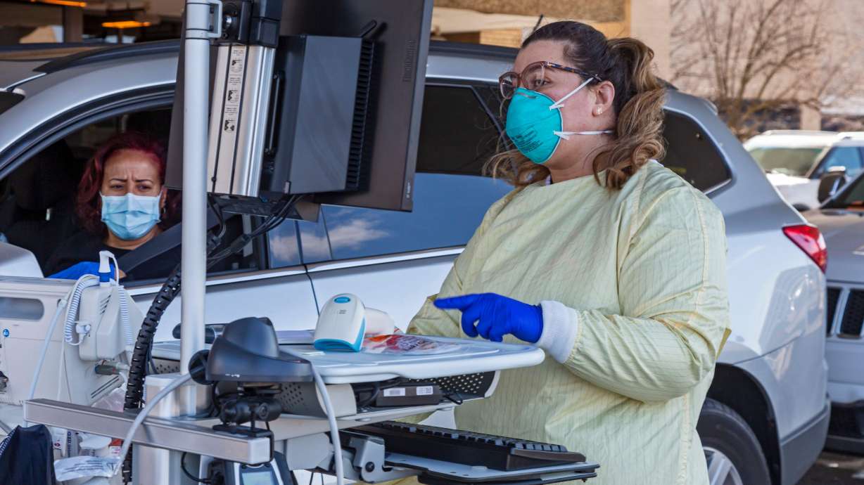 A health worker conducts drive-though testing for the COVID-19 virus outside Beaumont Hospital in Royal Oak, Mich., March 17, 2020